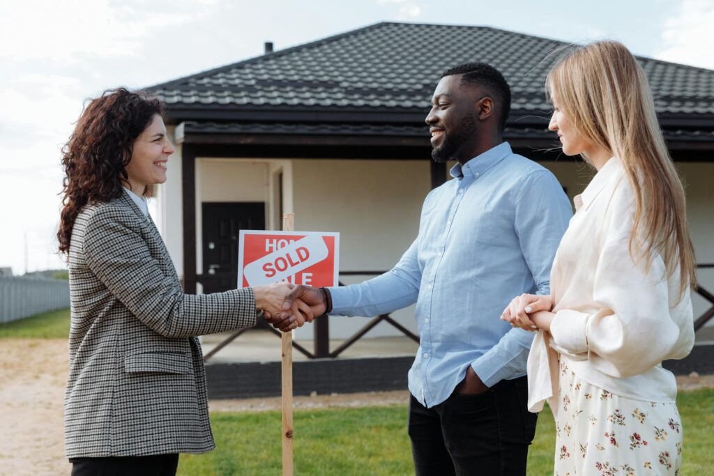 Real estate agent shaking hands with a couple after selling their home.