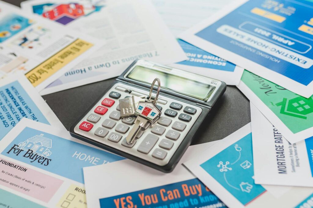 A calculator with a miniature shopping cart on top surrounded by financial papers.