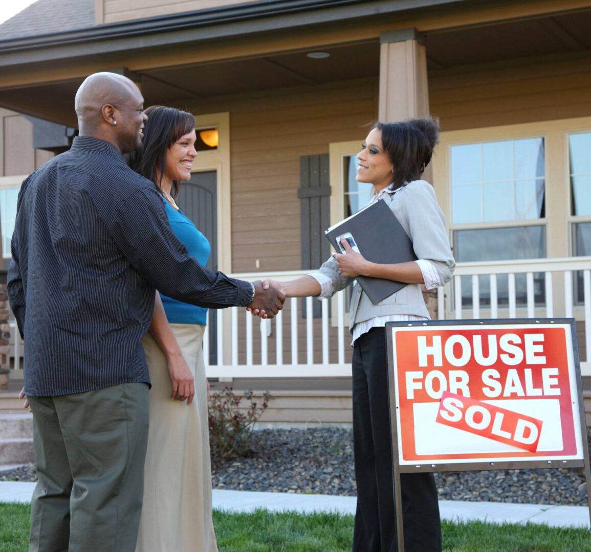 Couple shakes hands with real estate agent.